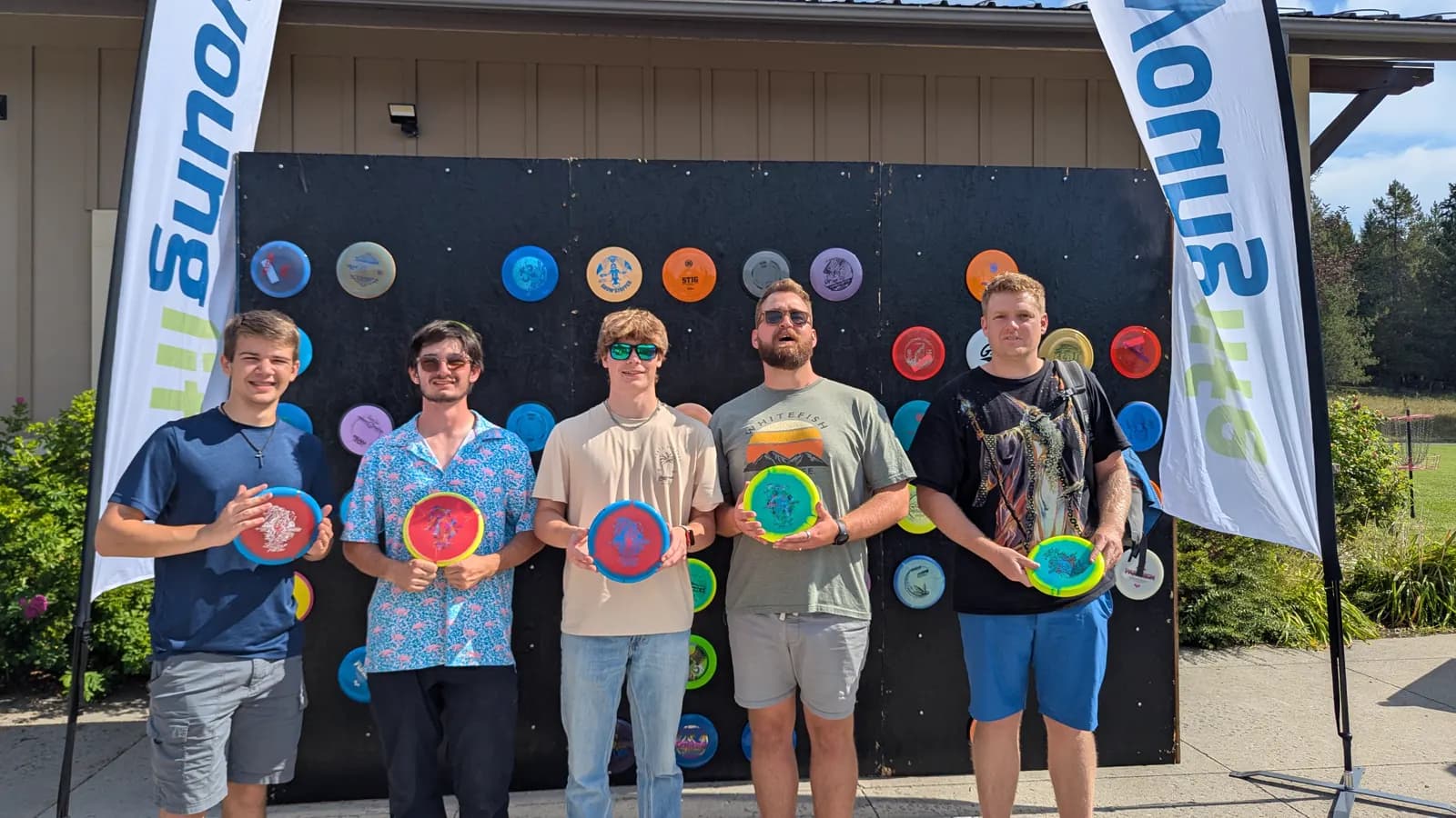 A 2025 scramble team holds custom discs after the round.
