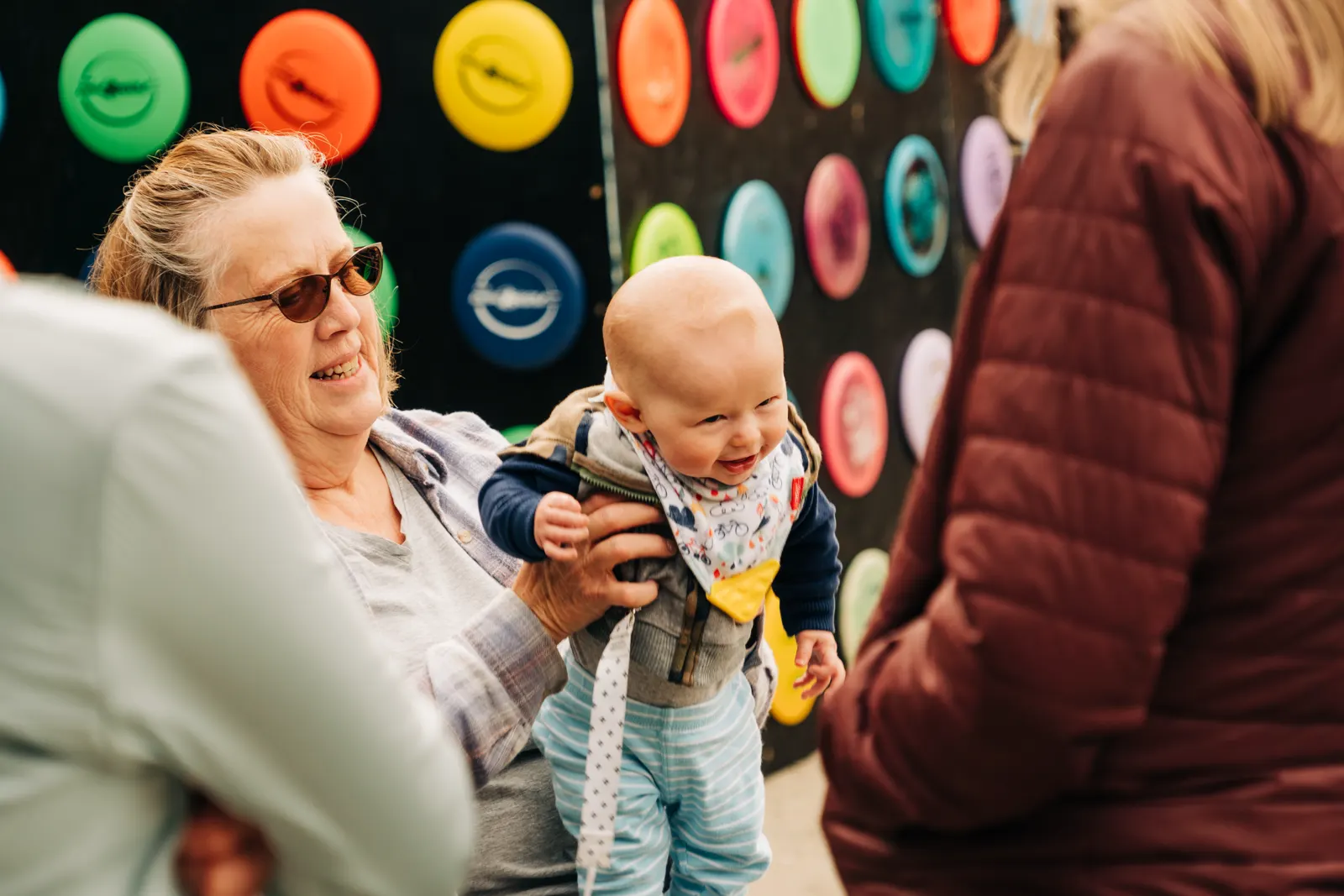 A smiling baby visits the Fish Toss disc wall.