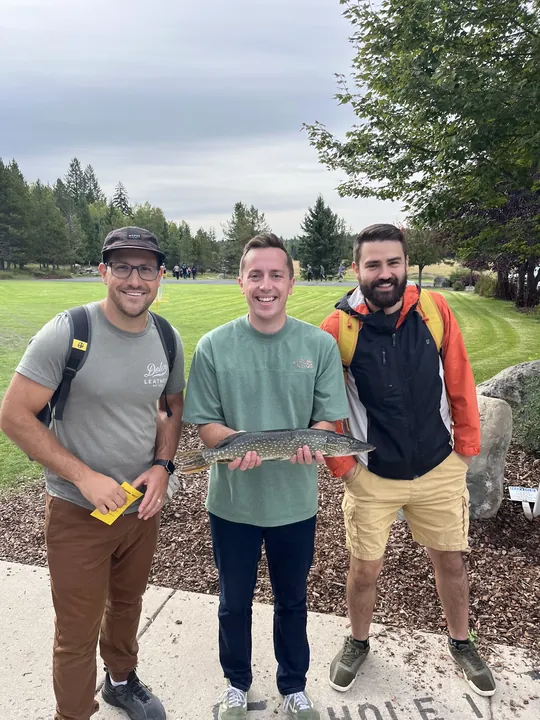 Joe holding a fish with two players